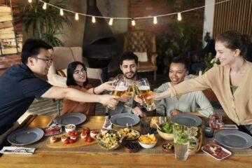 Diverse group of friends toasting glasses over a dinner table