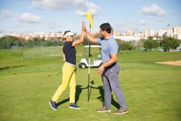 Two golfers giving high five on a sunny green